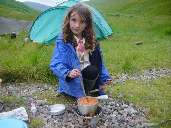A young girl stirring beans in a STORM CookKit pot